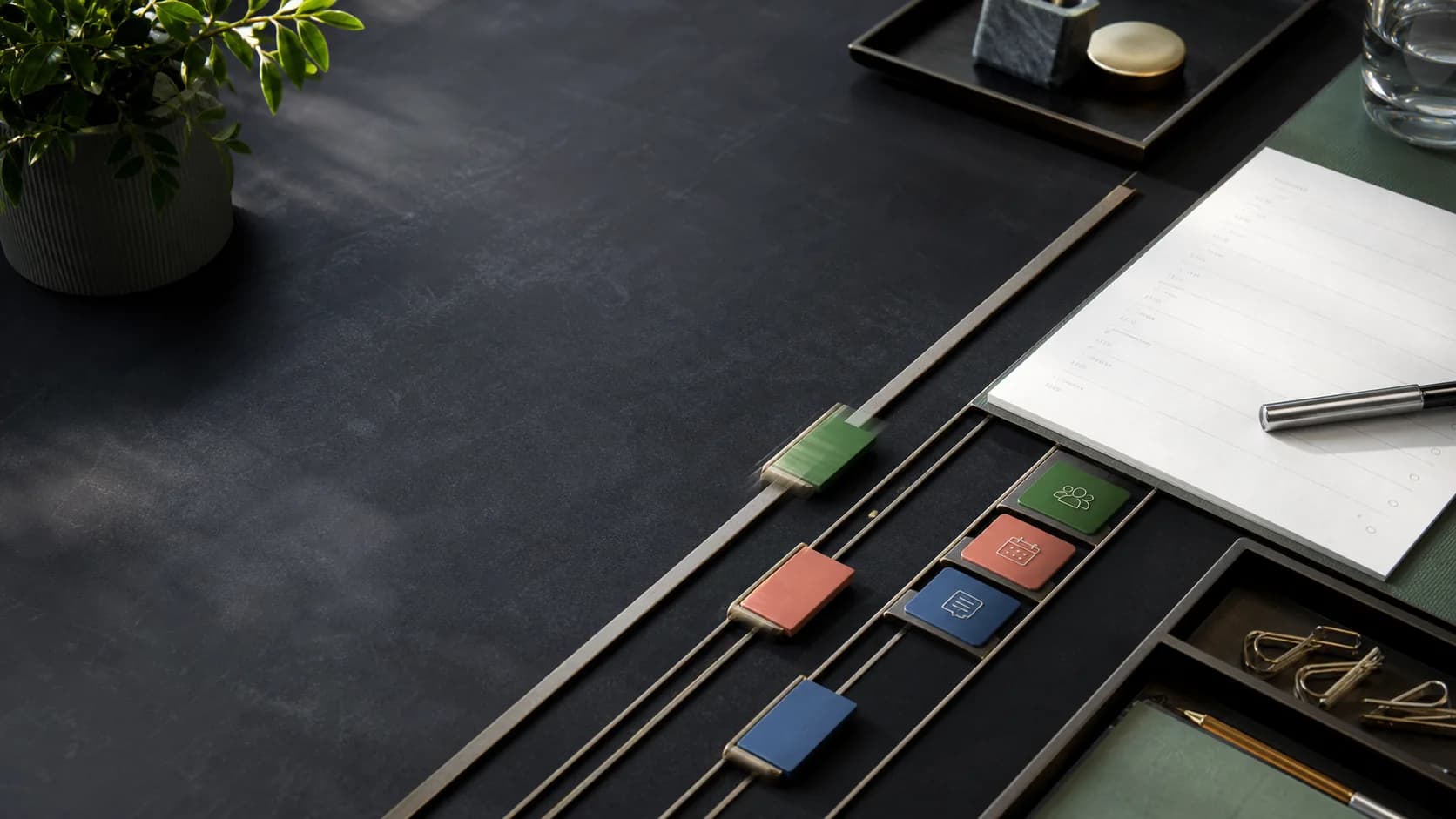 Tactile task markers moving through precise planning lanes on a dark desk